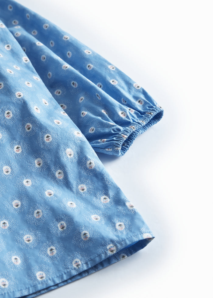 Blue children's dress with long sleeves, flounces, and small flowers.