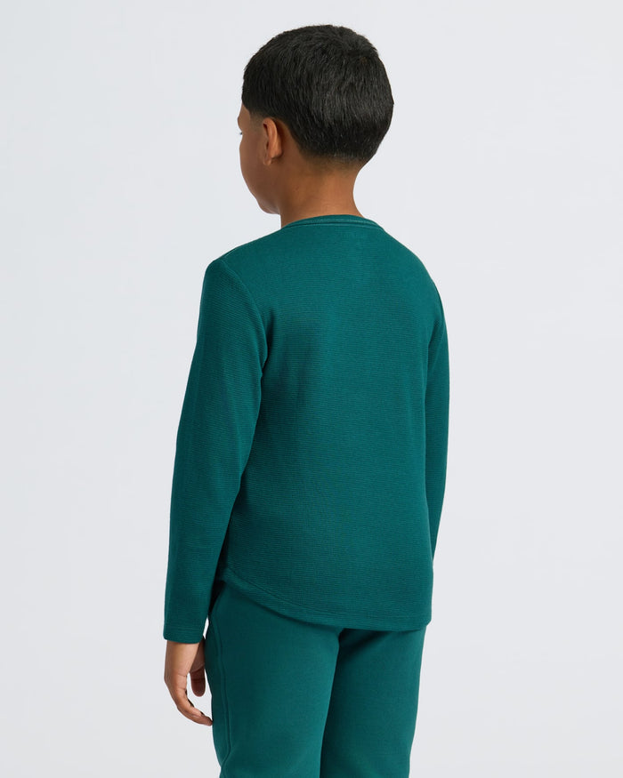 Child in Boys' Waffle Long Sleeve Henley, teal-green, jogger pants, back view.