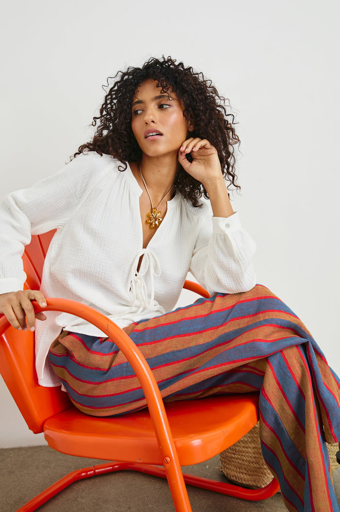 Brielle Long-Sleeve Top with a Deep V Neck with Ties and Pleats around the Neckline in White Colorway - Front View Featured on Seated Model