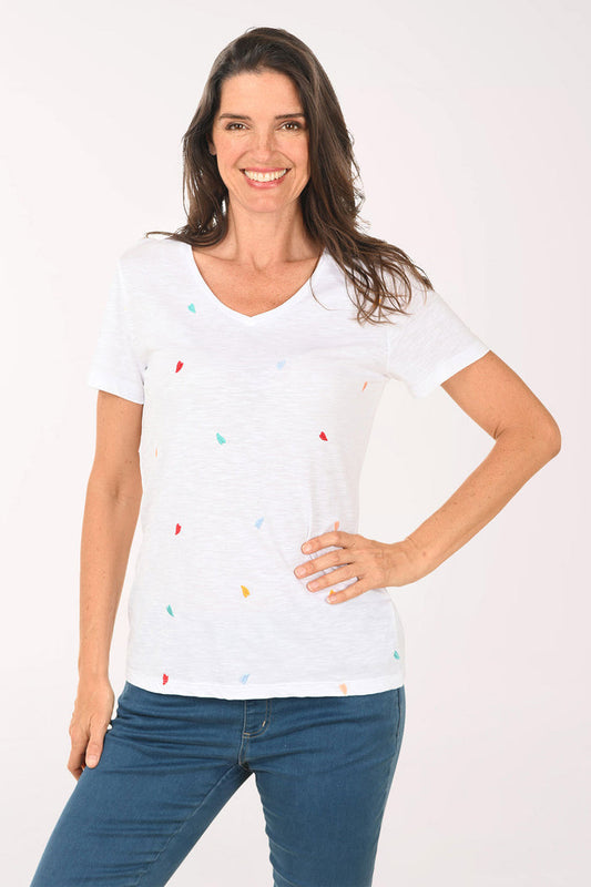 Woman wearing a white top with embroidered multi colored hearts