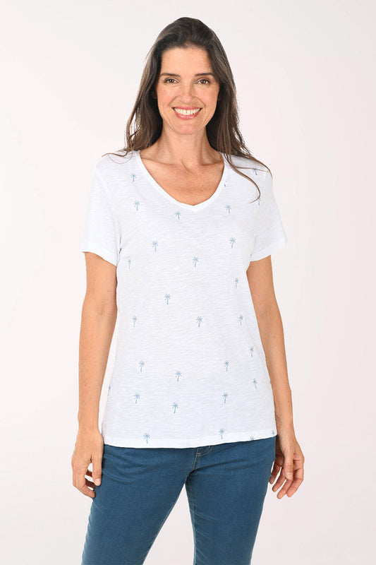 Woman wearing a white top with a palm tree pattern