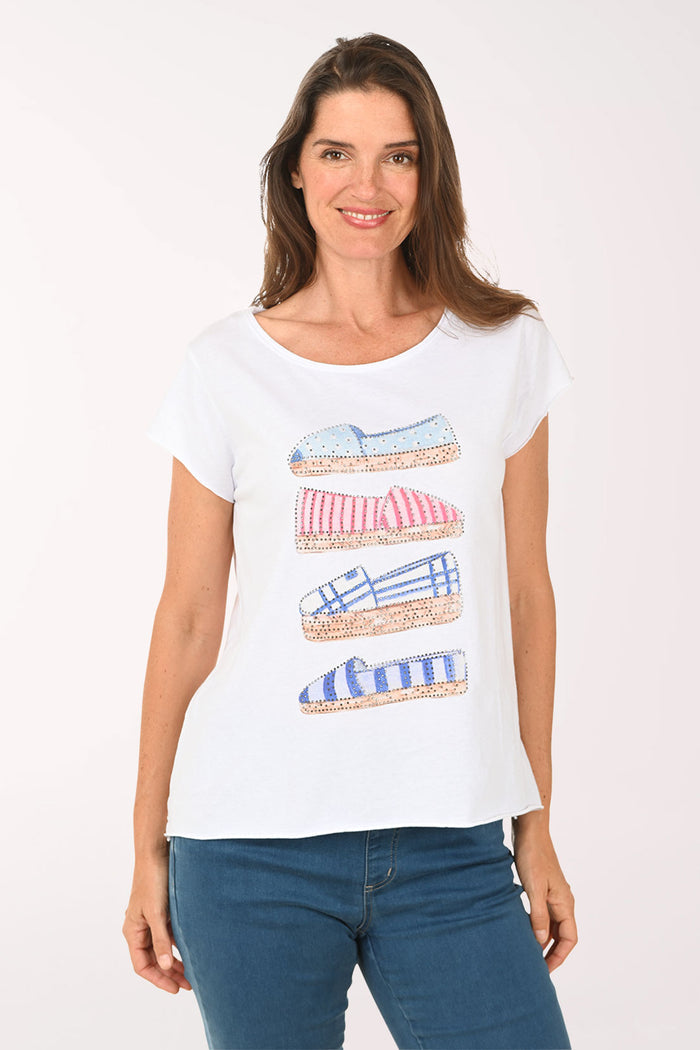 Woman wearing a white t-shirt with shoe designs on a plain background