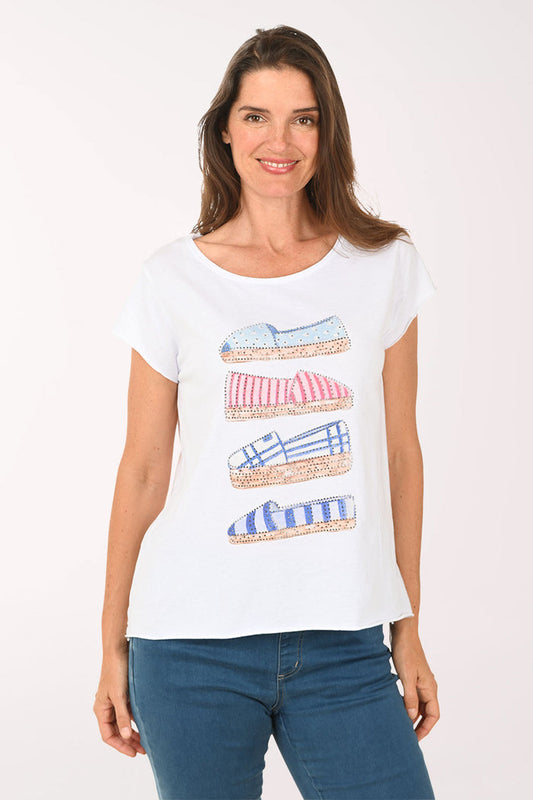 Woman wearing a white t-shirt with shoe designs on a plain background