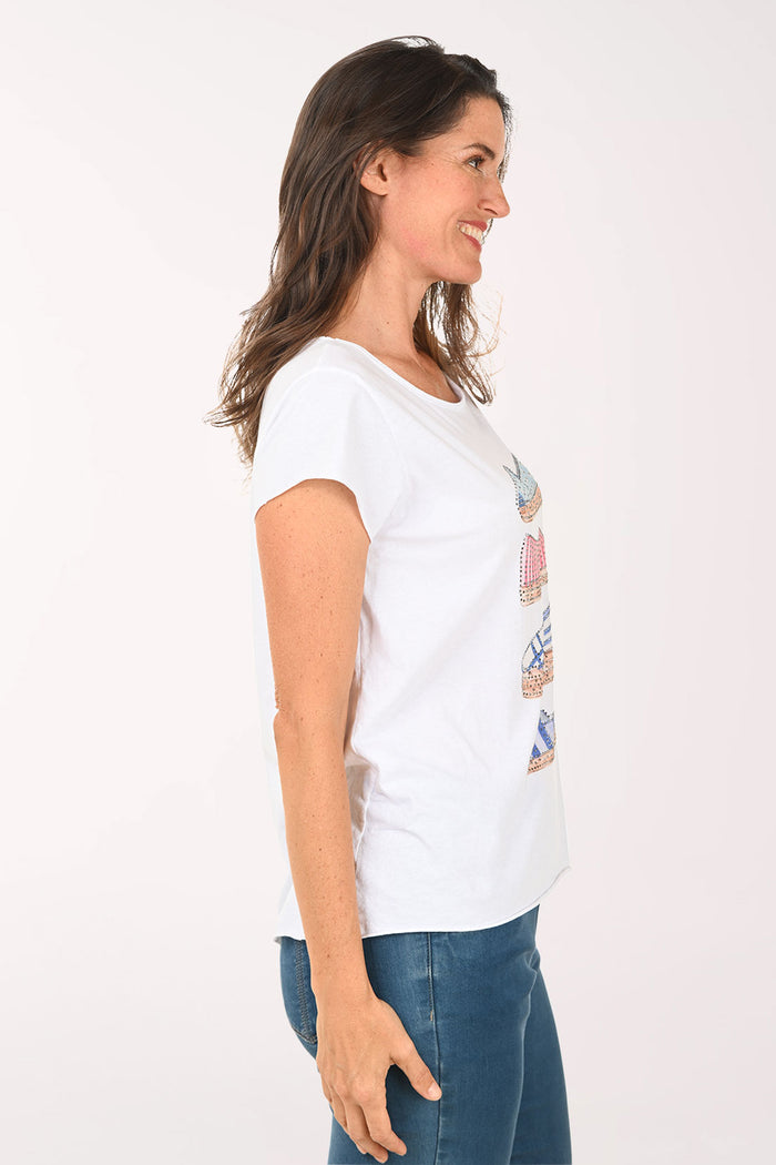 Woman wearing a white t-shirt with shoe designs on a plain background