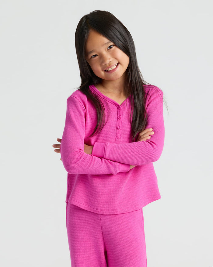 Girl smiling in Girls Electric Fuchsia Long Sleeve Boxy Waffle Henley.