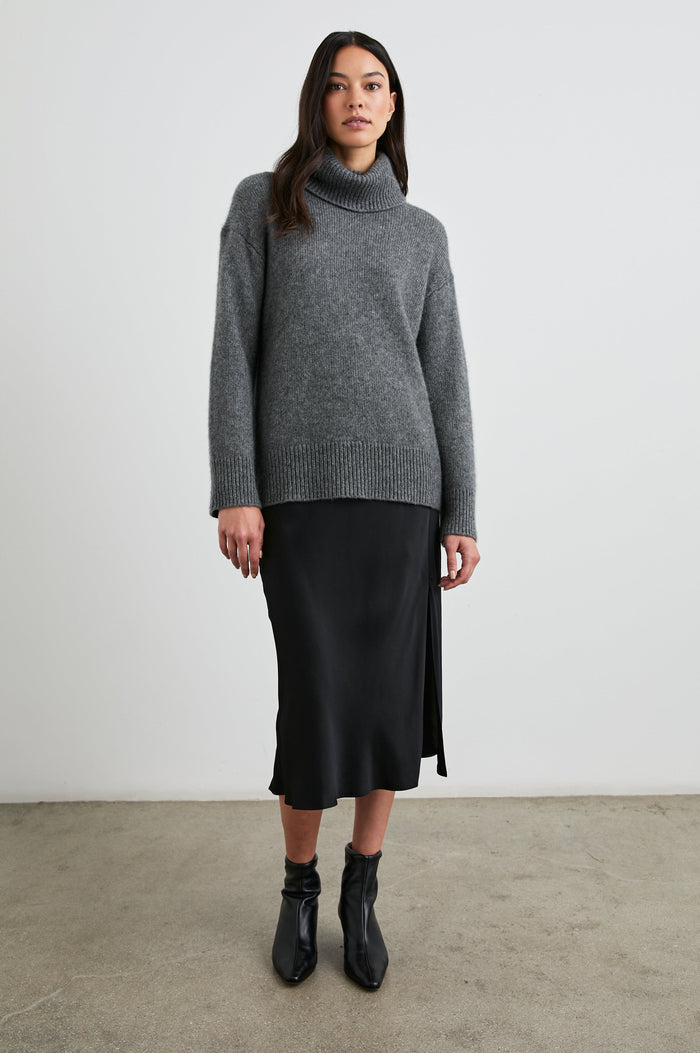 Maya Midi Skirt with Mid-Thigh Side Slit in Black Colorway - Front Full Body View Featured on Model