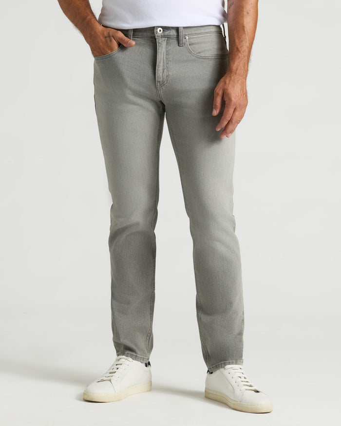 Medium Gray Wash Slim Authentic Denim Jeans and white sneakers on a model.