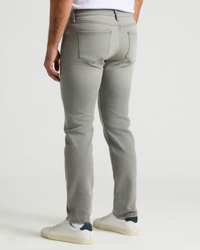 Medium Gray Wash Slim Authentic Denim Jeans and white sneakers, back view.