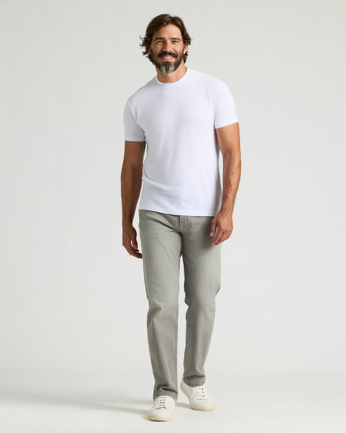 Man wearing Medium Gray Wash Straight Authentic Denim Jeans, white T-shirt, and sneakers.
