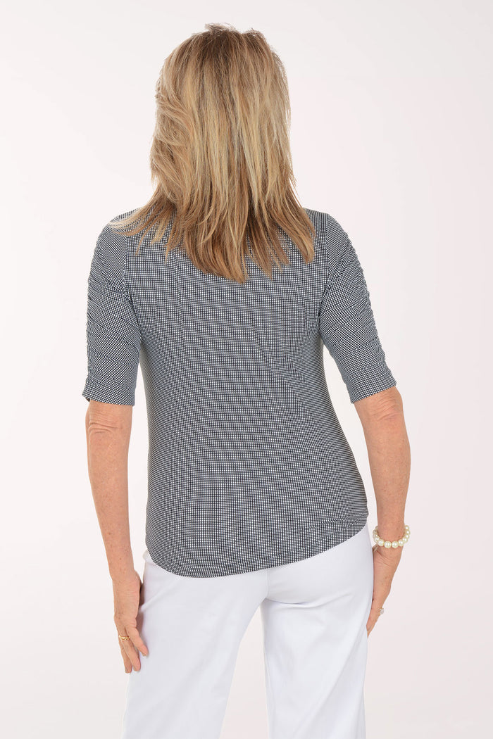 Woman wearing a black and white checkered short-sleeve shirt with a zipper on a white background. Back shot.