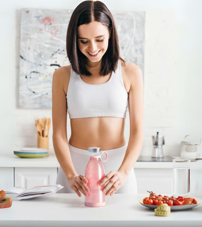 Pink portable juicer blender bottle with loop handle on tabletop