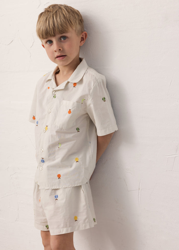 Children wearing a t-shirt and shorts with fruit embroidery.