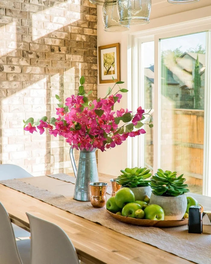 Artificial bougainvillea stems with pink blooms and green leaves in a metal vase