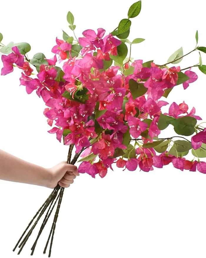 Artificial bougainvillea stems bundle with bright pink flowers and green leaves, held by hand