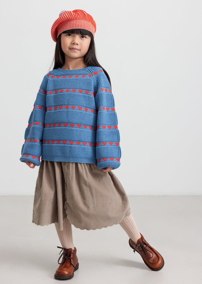 Girl wearing beige baby velvet skirt and striped blue blouse