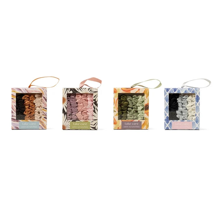 DM Merchandising set of four take care satin scrunchies in assorted colors and patterned packaging