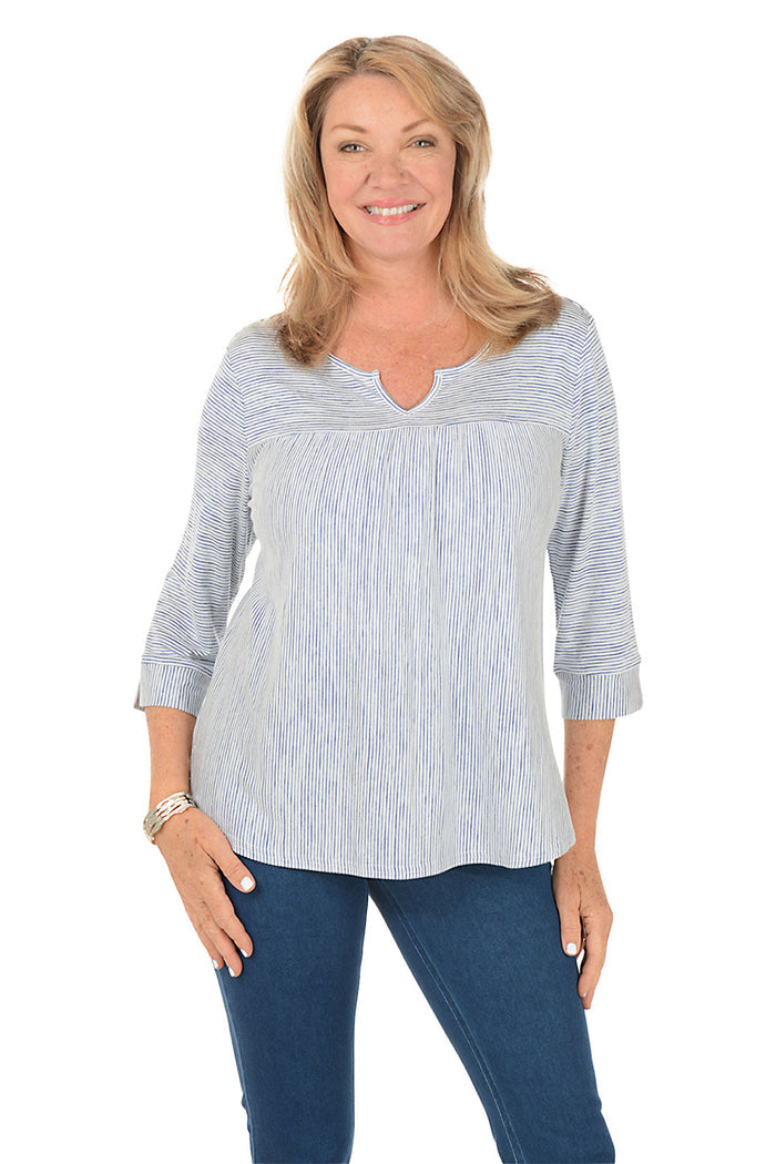 Woman wearing a blue and white striped shirt and blue jeans on a white background.