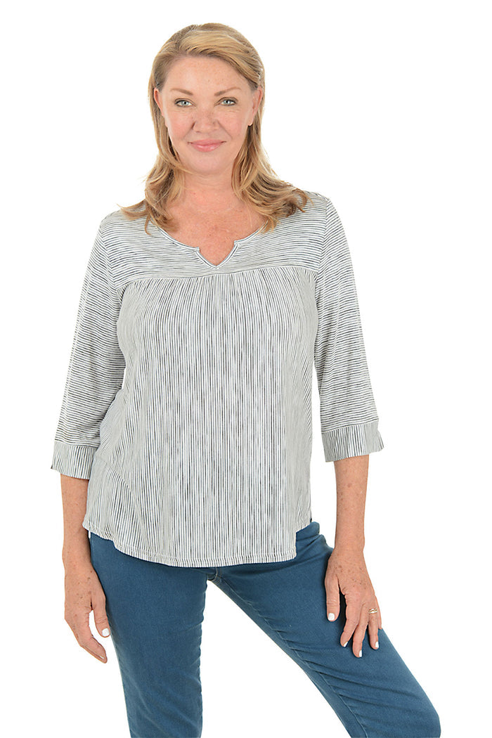 Woman wearing a black and white striped shirt and blue jeans on a white background.
