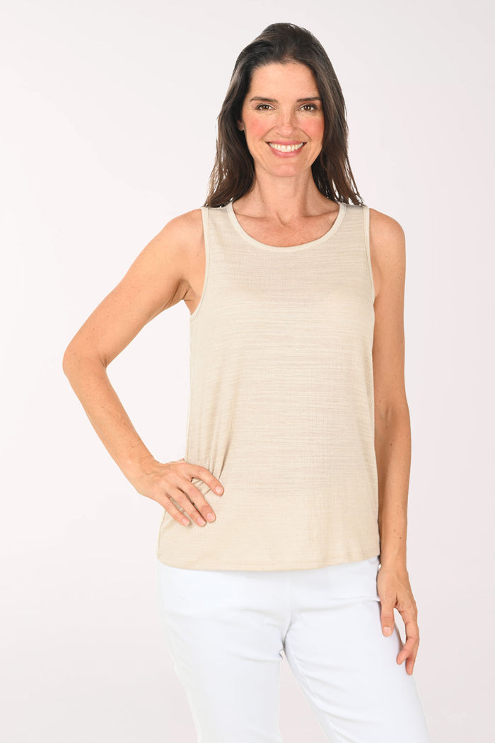 Woman wearing a beige sleeveless top and black pants on a white background