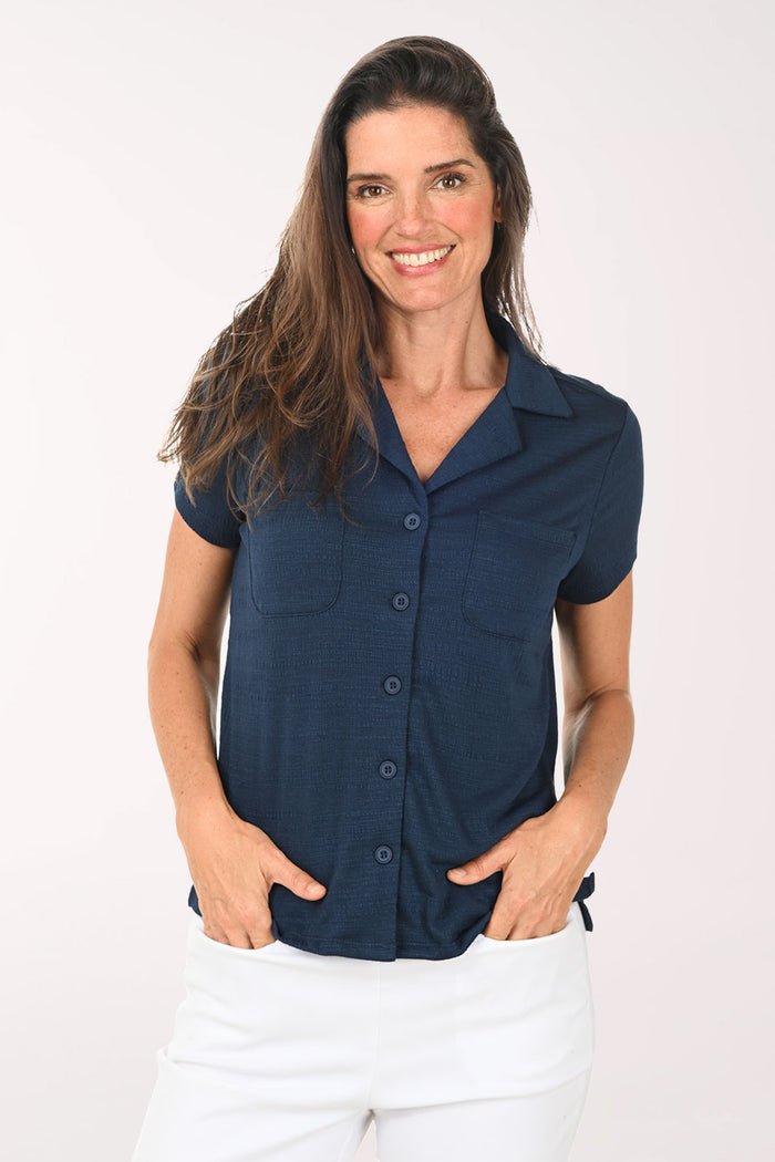 Woman wearing a navy blue button-up shirt with short sleeves on a white background