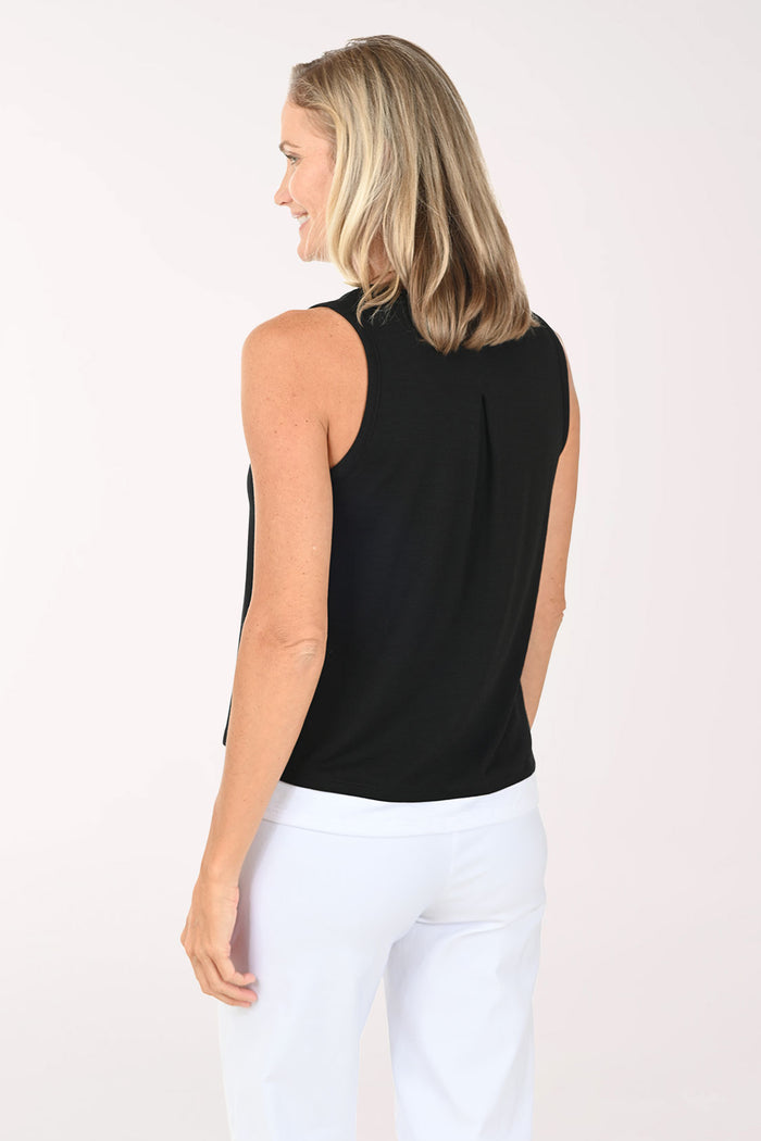 Woman wearing a black sleeveless top and white pants on a white background