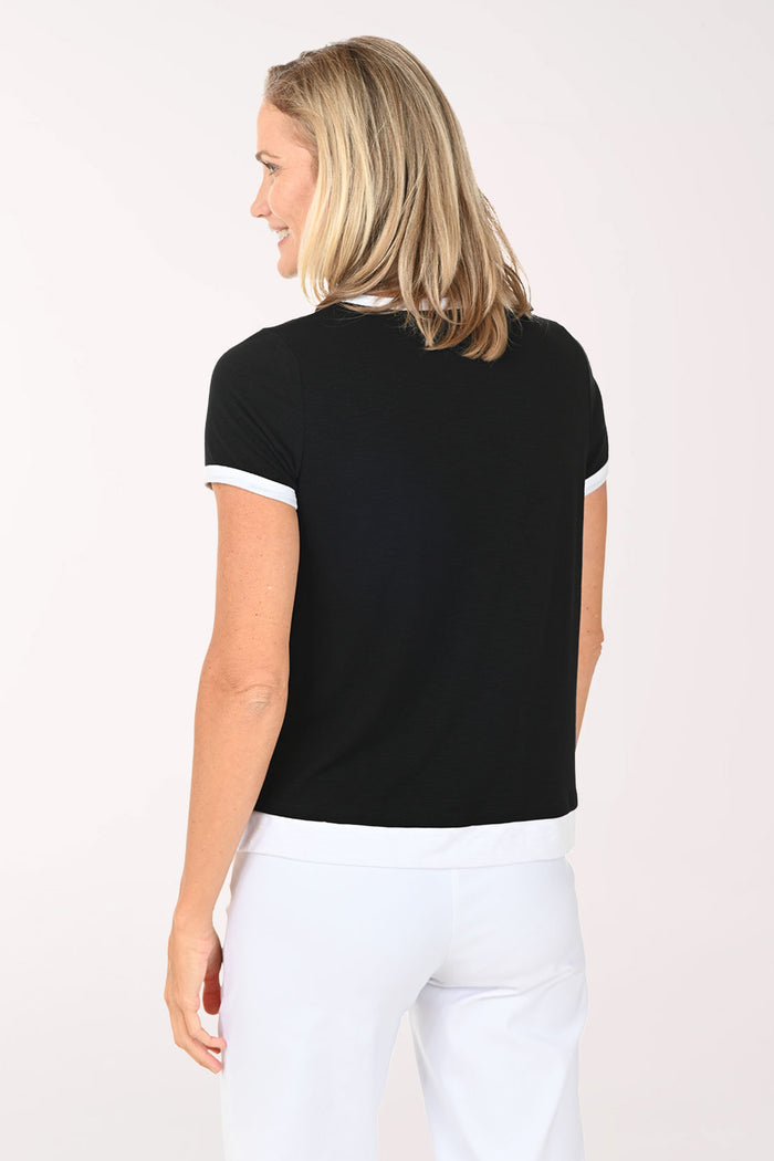 Woman wearing a black top with white trim and white pants on a white background