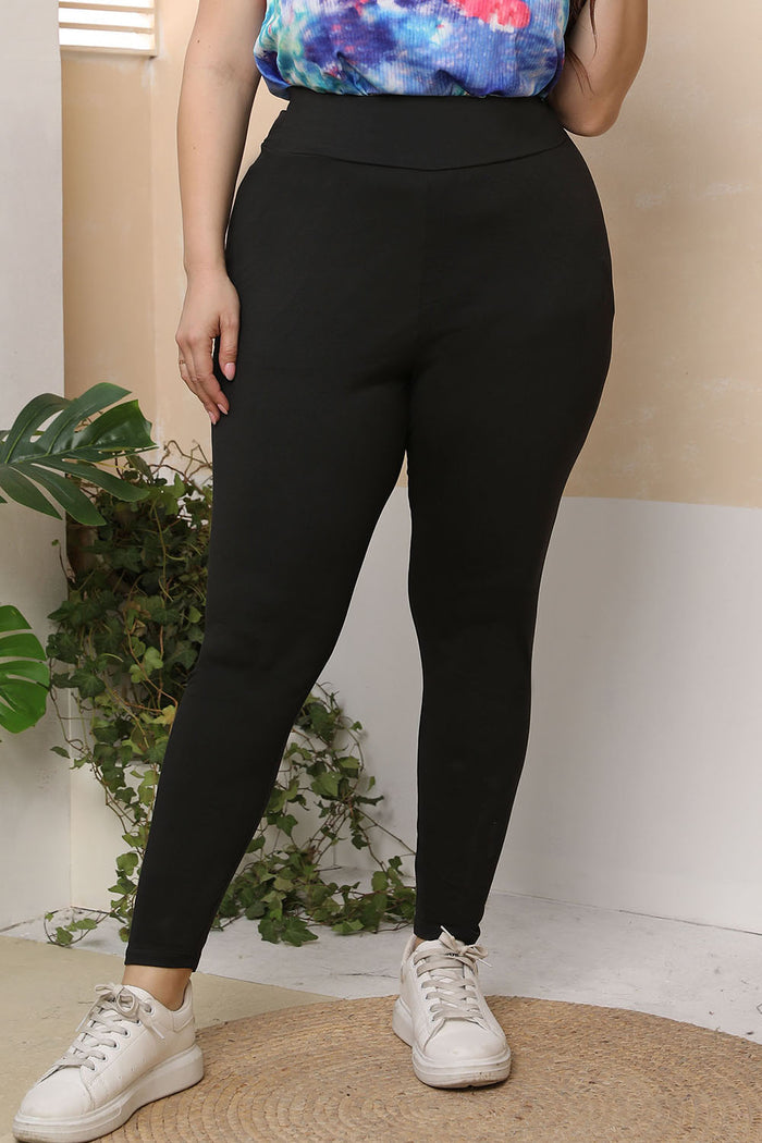 Woman wearing black plus size skinny pants paired with white sneakers and a colorful top
