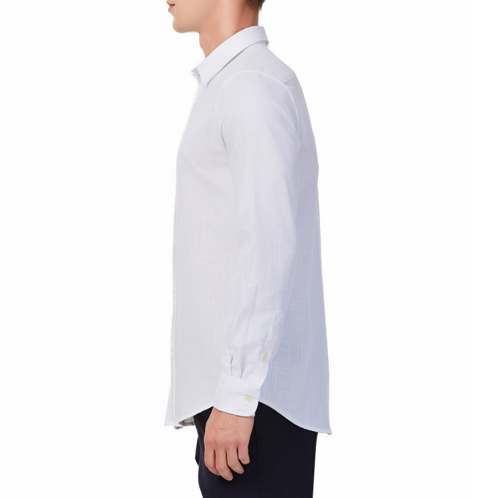 Men's white textured linen long sleeve button up shirt with a pointed collar on a model. Image is cropped to the torso and model is facing to the side so the arm is facing the viewer